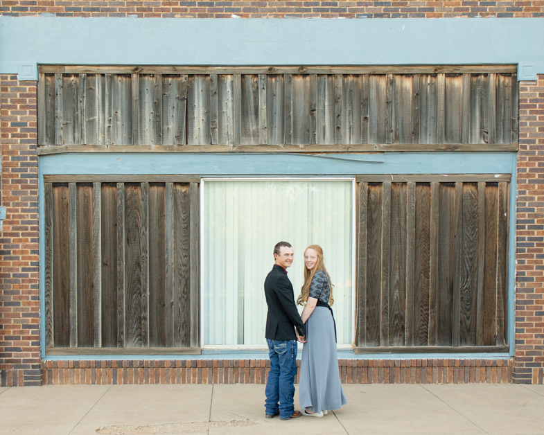 Couple smiling at camera in front of rustic building