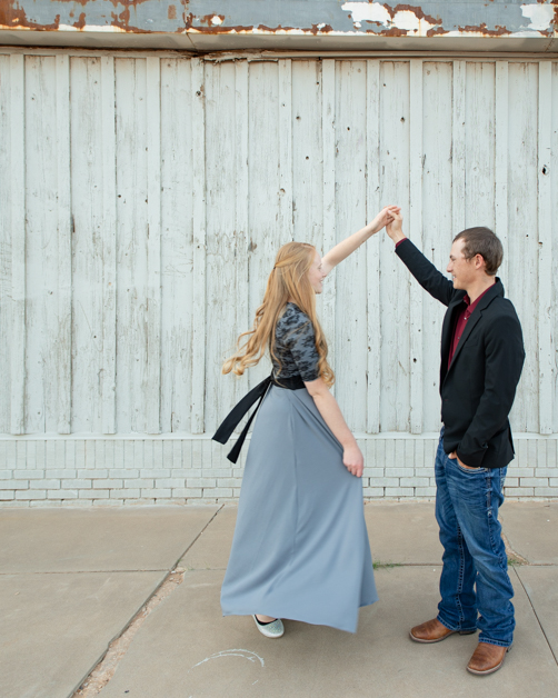 Man twirling his girlfriend in front of old building