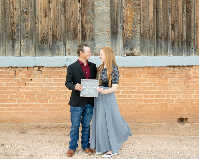 couple holding letter board in front of rustic building