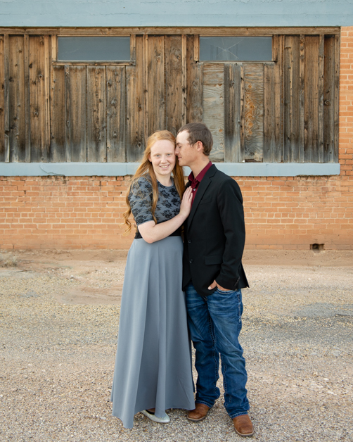 engaged couple in front of rustic building